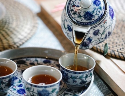 tea pot pours tea into cup