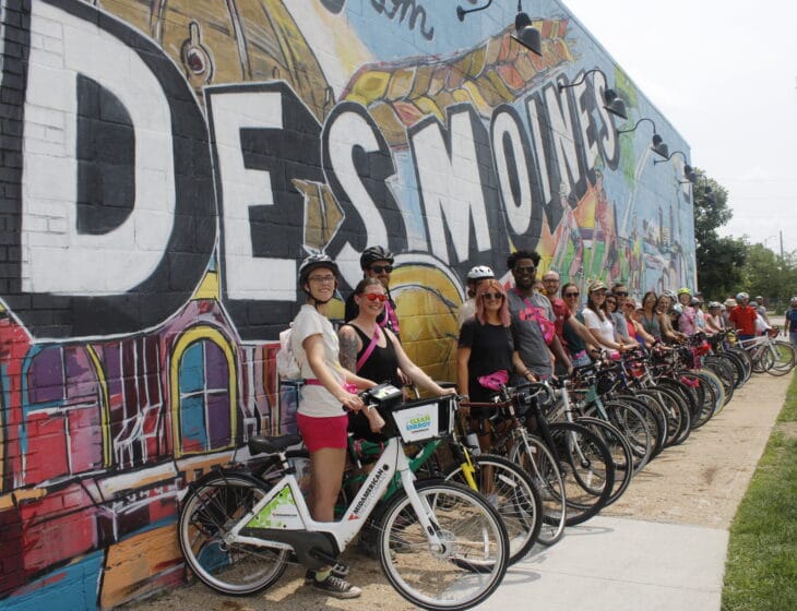 people on bikes parked in front of Des Moines mural