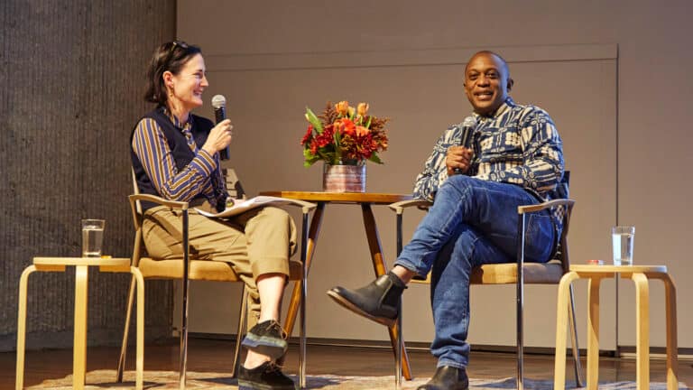 Art Center Director Kelly Baum sits across from artist Hank Willis Thomas on stage.