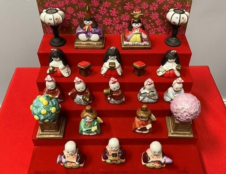 Traditional Japanese doll display on tiered red showcase.