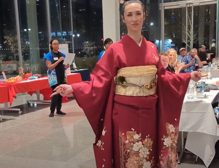 Japanese kimono fashion show; person standing wearing a red and gold colored kimono.