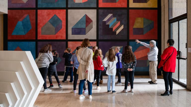 Kids in the art museum on a school tour looking up at a colorful artwork on the wall