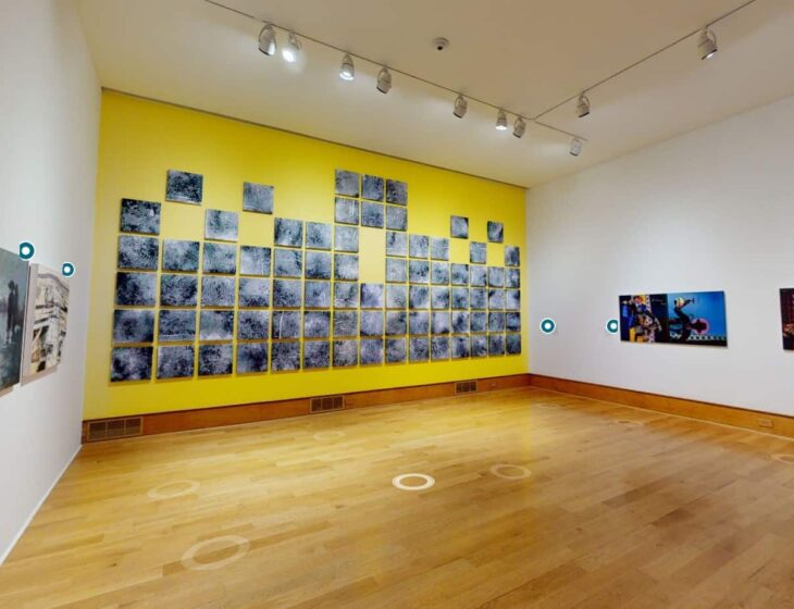 View of the first gallery space in the virtual tour of "States of Becoming," with three walls of artwork showing. Two painting on each wall opposite each other, then a yellow painted wall in front with a salon wall of large fingerprints on canvas.