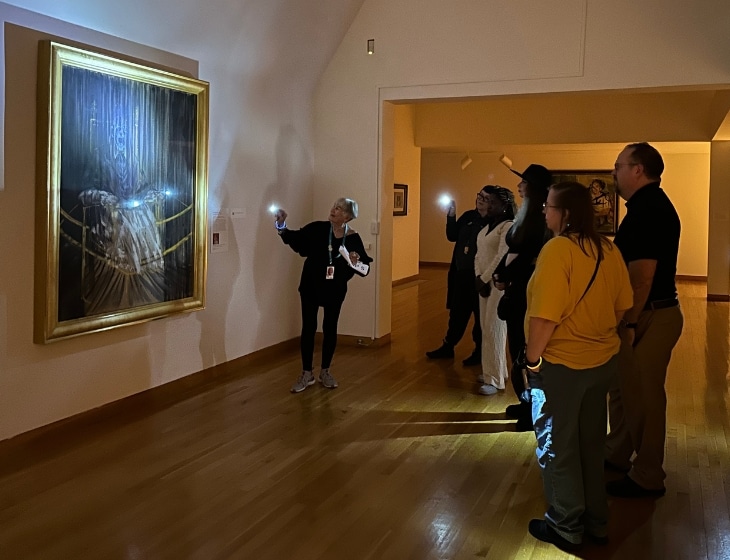 2024 Art Noir flashlight tour - visitors viewing artwork by the glow of a flashlight.