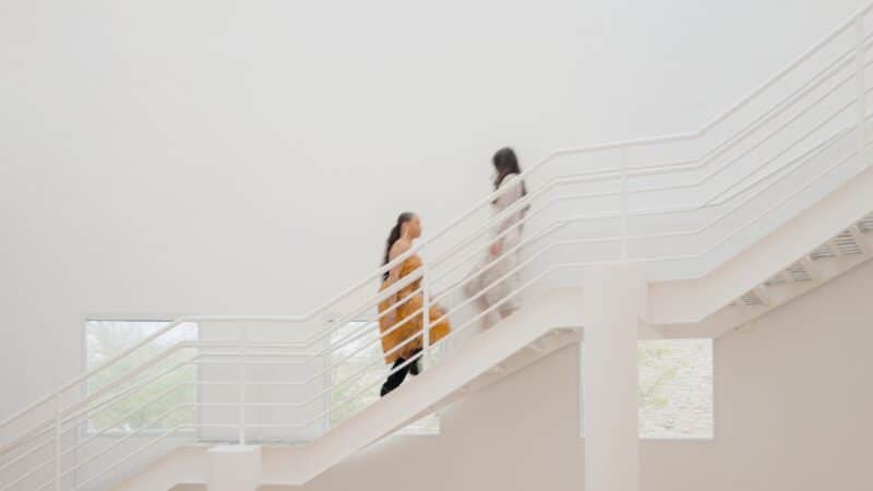 Two women walking past each other on the white Richard Meier staircase of the Art Center.