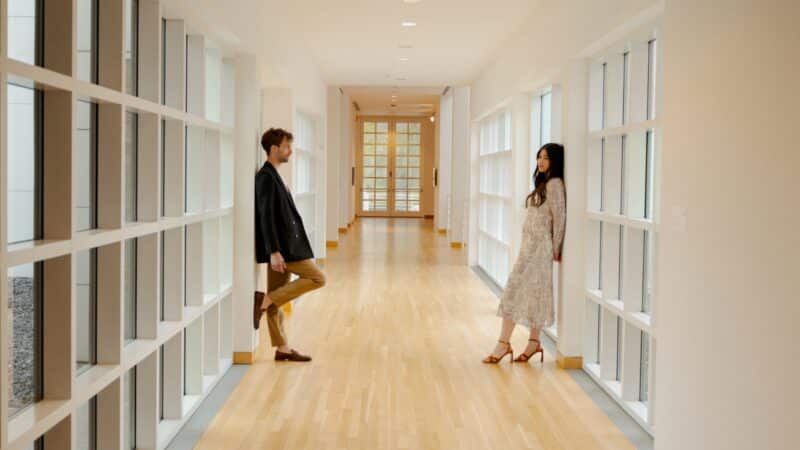 Two people in the Richard Meier building hallway, surrounded by square white windows.