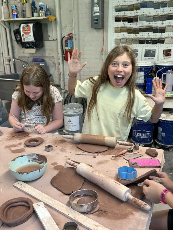 Two youth in an art studio working on clay projects