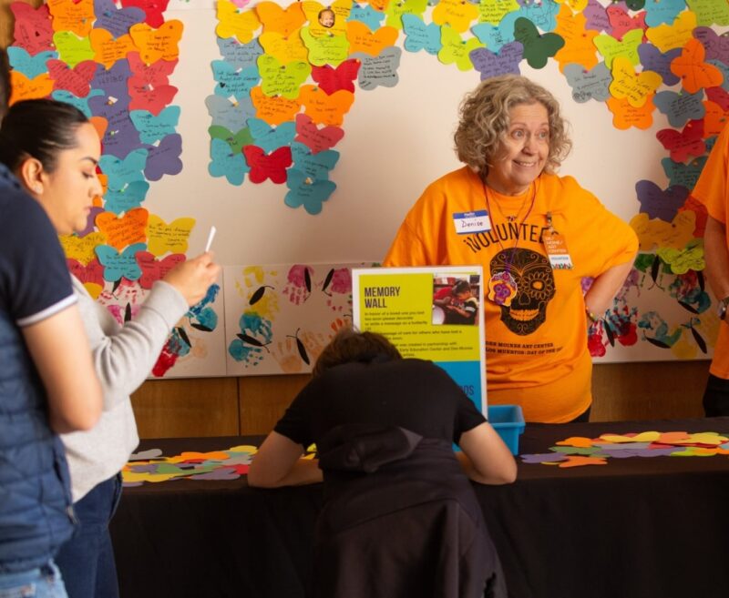 Volunteer at the Day of the Dead celebration standing behind a table