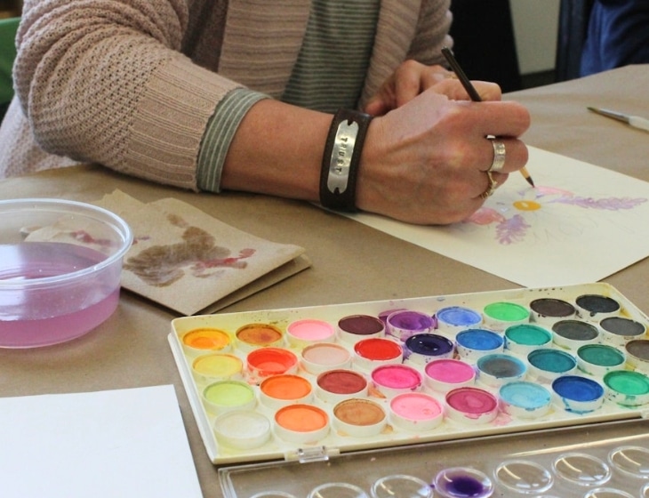 Person working on a painting with a watercolor palette
