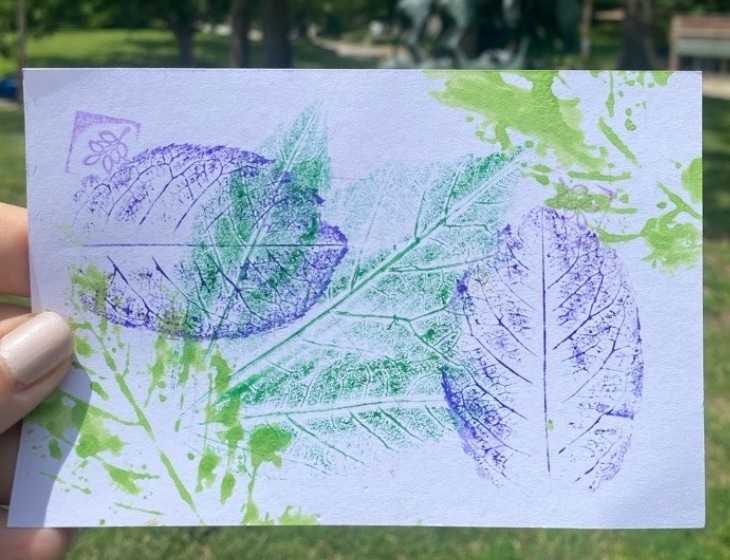 White postcard paper with stamped forms of leaves and branches in colors green and blue.